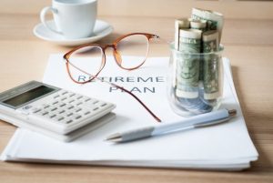 Retirement plan papers on a desk with a calculator and pen