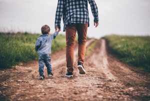 Father and child walking down path holding hands