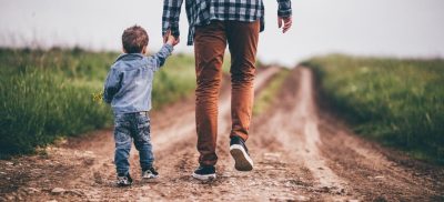 Father and child walking down path holding hands